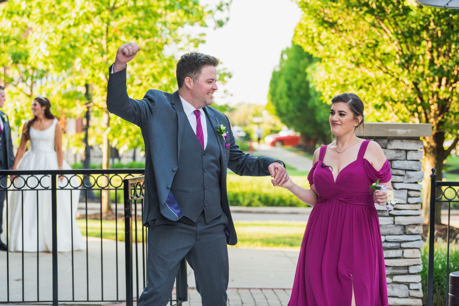 Bridesmaid and groomsman, bridal party entrance, dancing, fun bridal party entrance, metal fence, green trees, sweet wedding reception at Crocker Park, Westlake OH