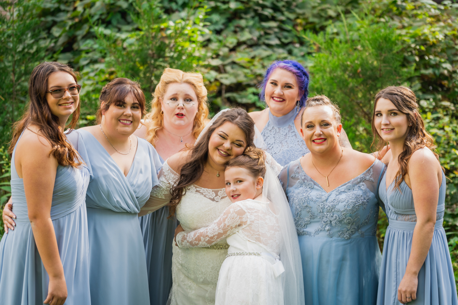 Bride with bridesmaids and flower girl, bridal party portrait, cute, hug, green, trees, nature, outdoor September wedding ceremony at Westfall Event Center