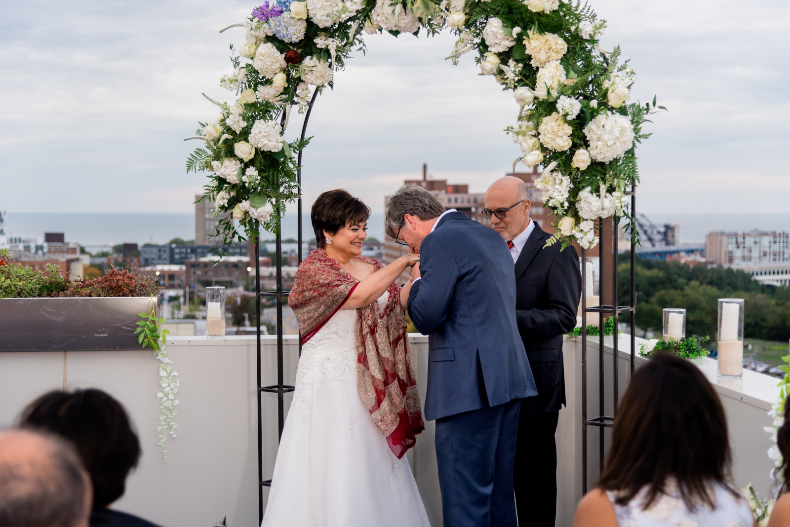 Groom kisses bride's hand, wedding ceremony, sweet, cute wedding photo, older couple, romantic outdoor urban wedding ceremony at Penthouse Events, Ohio City, Cleveland Flats, downtown Cleveland skyline, Lake Erie