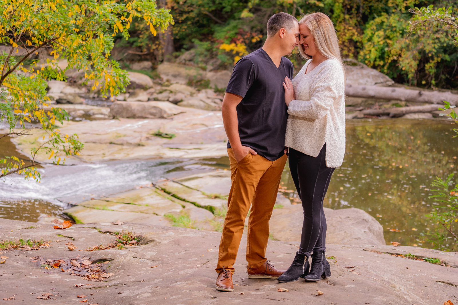 Man and woman fiancee engagement photo, couple portrait, romantic, creek, fall leaves, fall colors, trees, nature, outdoor fall engagement photo session at Grand Pacific Junction Historic Shopping District