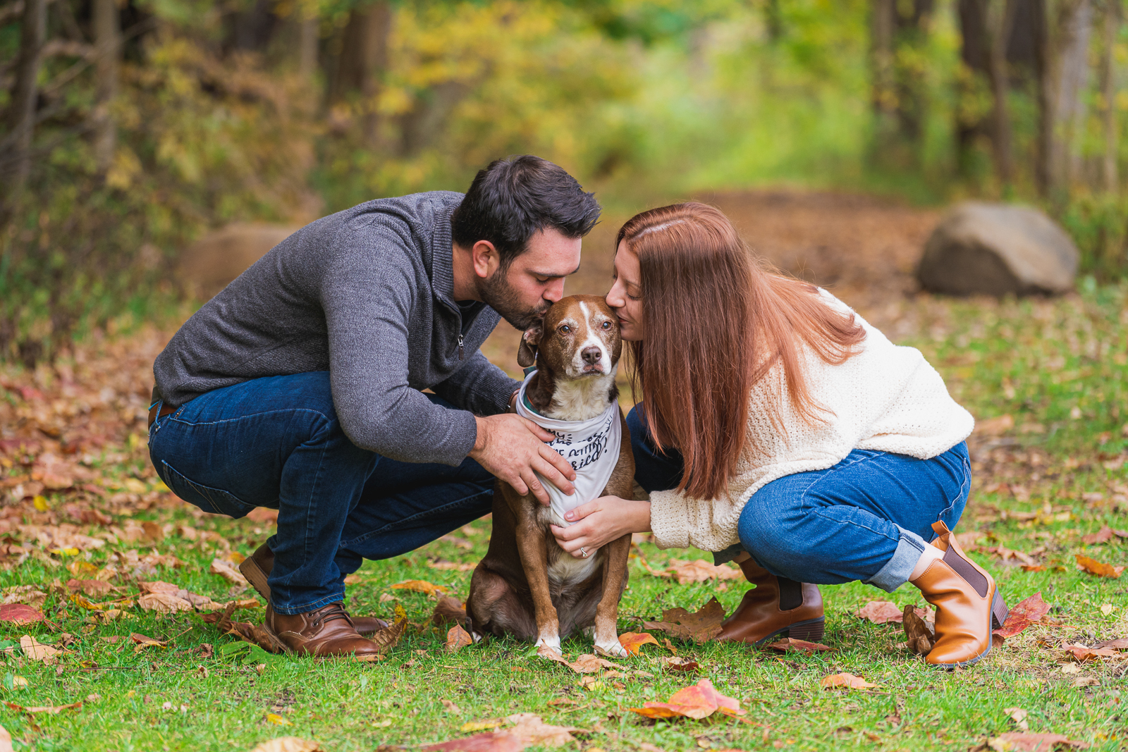 Man and woman fiancee engagement photo with dog, kiss, cute dog, dog bandana, outdoor, nature, forest, fall leaves, fall colors, outdoor fall engagement photo session at Tinkers Creek, Bedford Reservation, Cleveland Metroparks