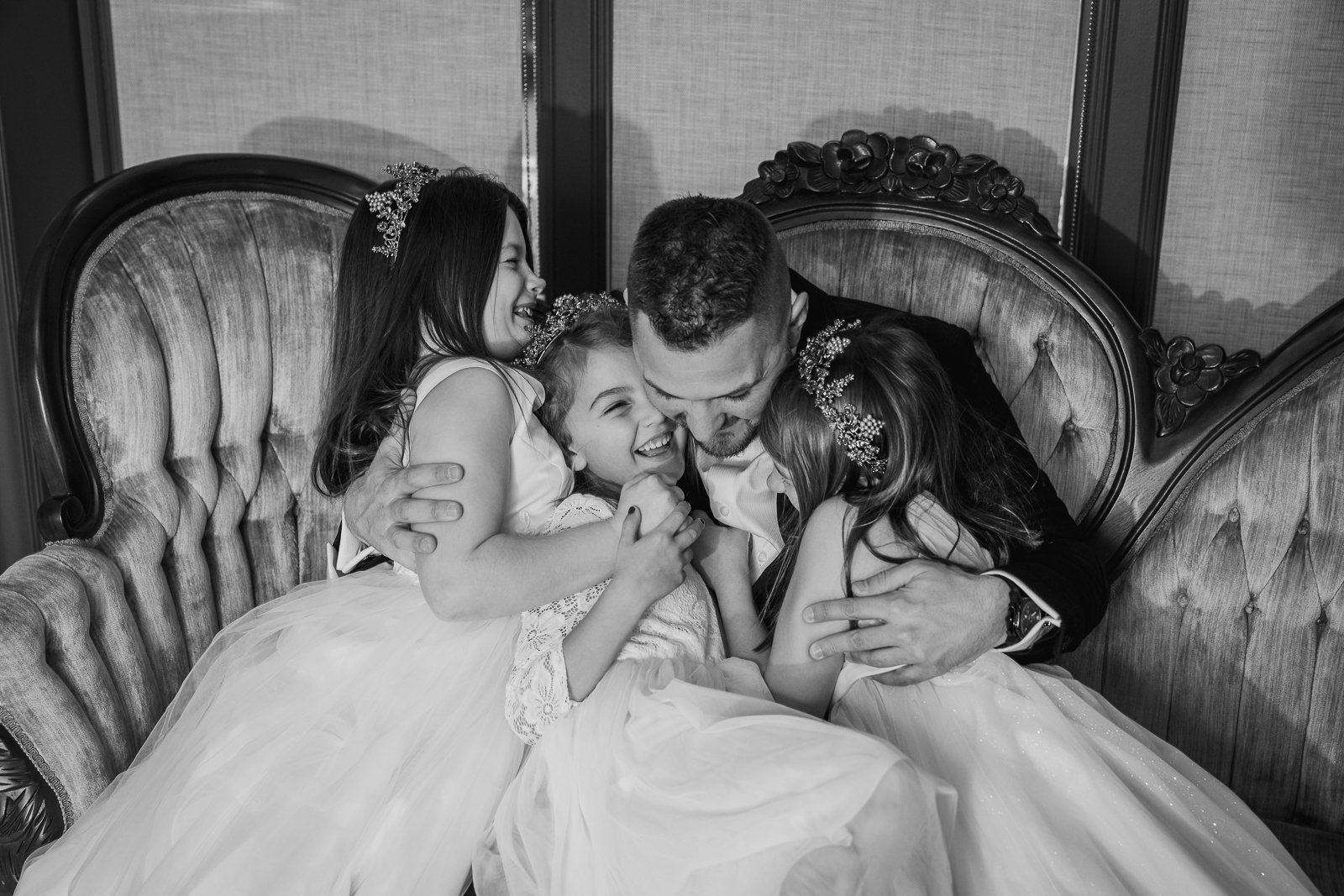 Groom hugging daughters, flower girls, before wedding ceremony at Gather at the Lakes