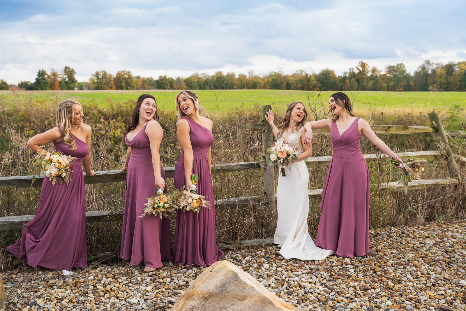 Bride with bridesmaids, smile, laugh, bridal party portrait, fun bridal party portrait, field, fence, nature, fall wedding, outdoor wedding ceremony at White Birch Barn